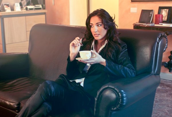 Woman In Black Blazer Holding Teacup While Sits On Black